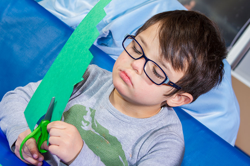 boy cutting paper with a scissors | Occupational Therapy